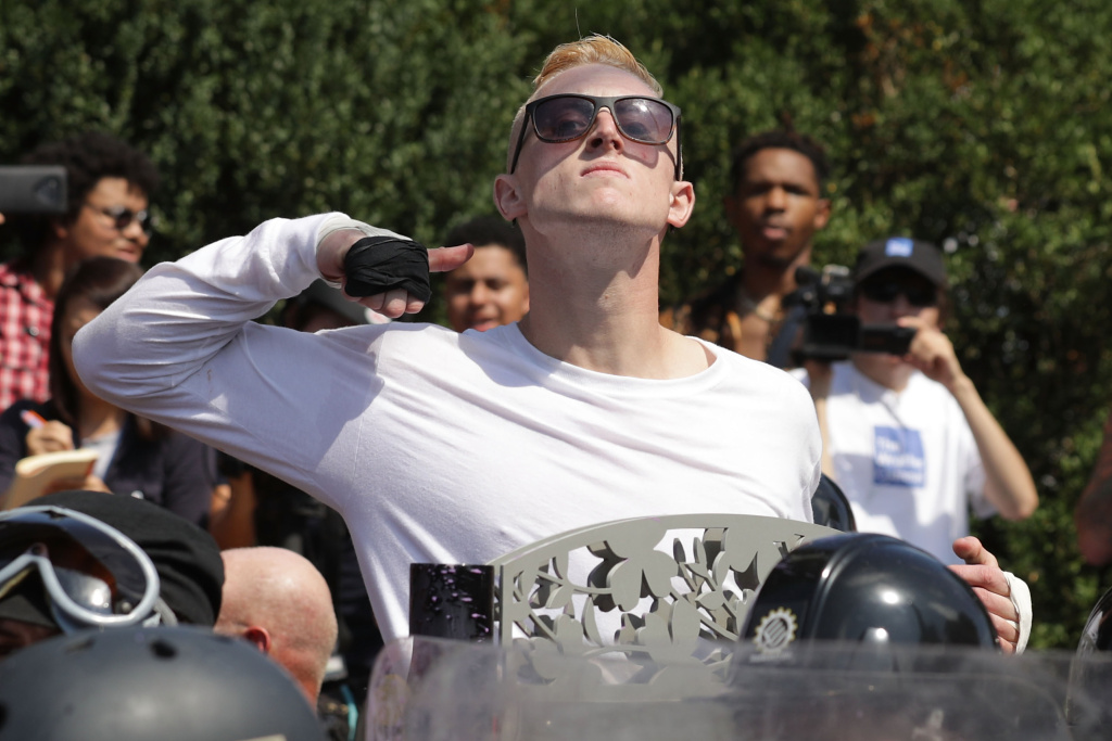 A man marching with white nationalists makes a slashing motion across his throat toward counter-protester in Charlottesville's white pride rally. (Chip Somodevilla/Getty Images)