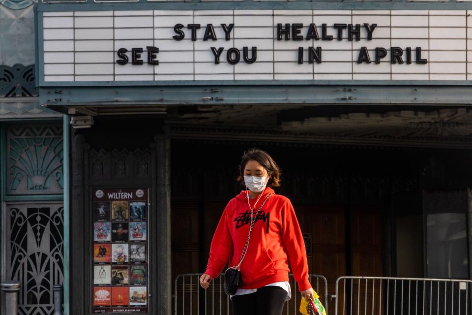 A woman walks wearing a mask to protect herself from the novel coronavirus (COVID-19) in front of a closed theater in Koreatown, Los Angeles, on March 21, 2020. (AFP, GETTY IMAGES)